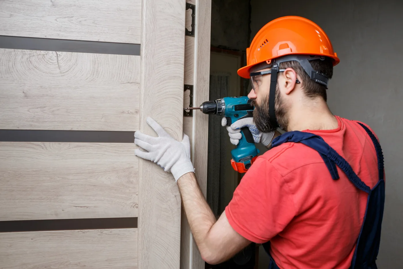 Artisan serrurier posant un bloc-porte et ses paumelles dans un logement des Mureaux